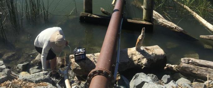 Delta Science Fellow Joseph Fackrell sets up equipment to sample the San Joaquin river from the Sherman Island levee. 